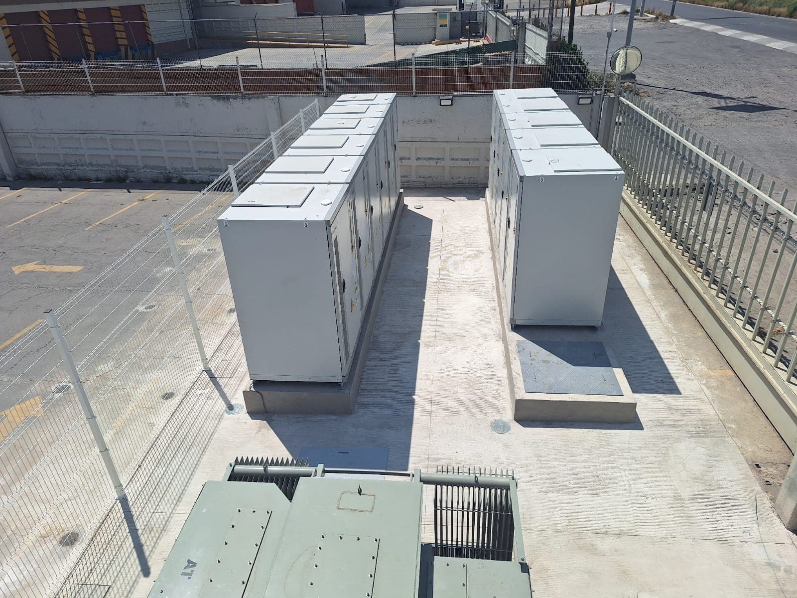 Dos grandes gabinetes eléctricos industriales grises instalados en una plataforma de concreto exterior cercada.