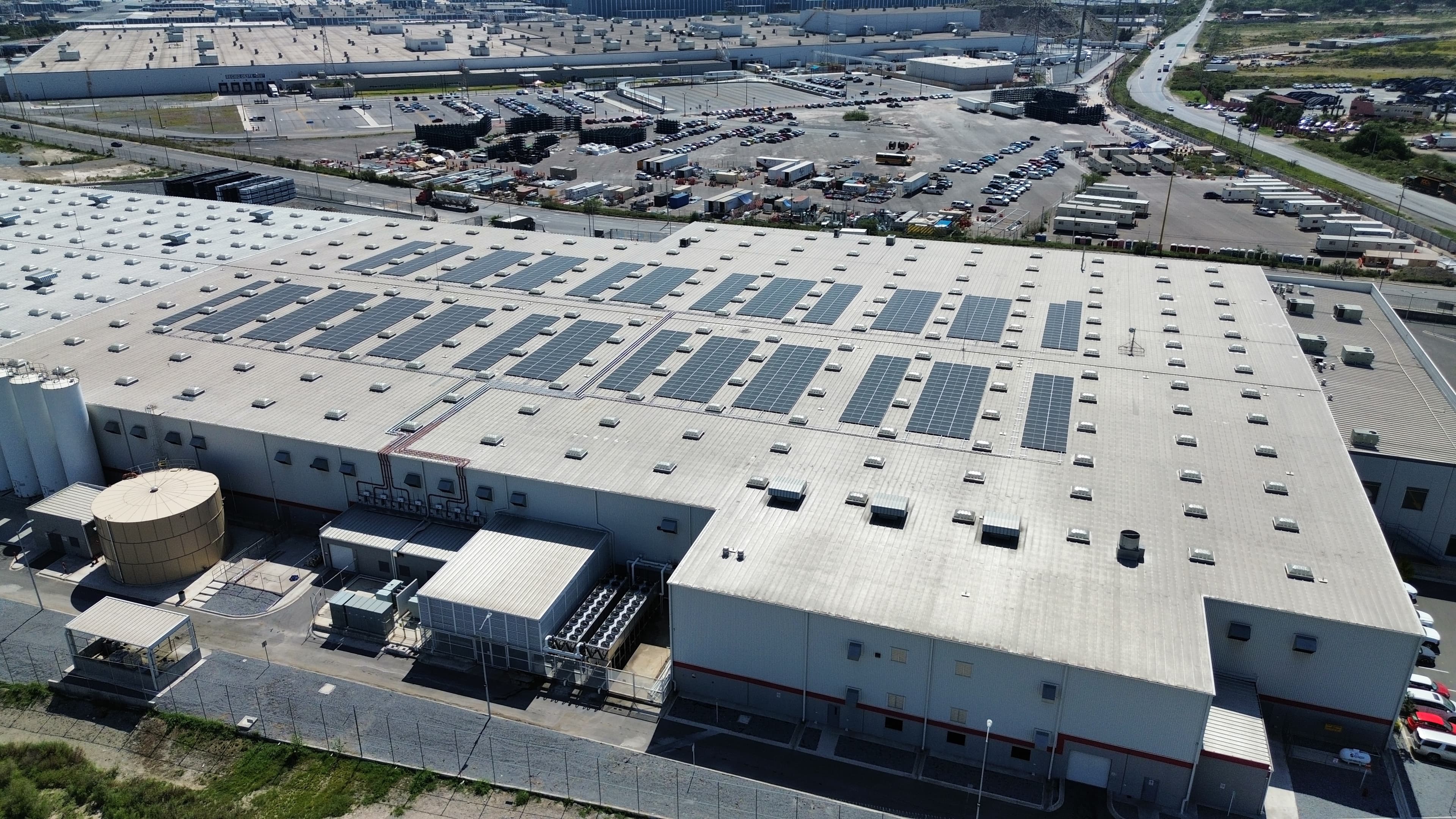 Vista aérea de un gran almacén industrial con numerosos paneles solares en su techo.